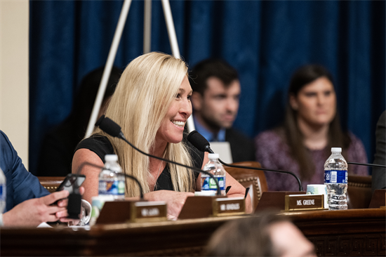 Rep. MTG smiles from her chair during a committee hearing